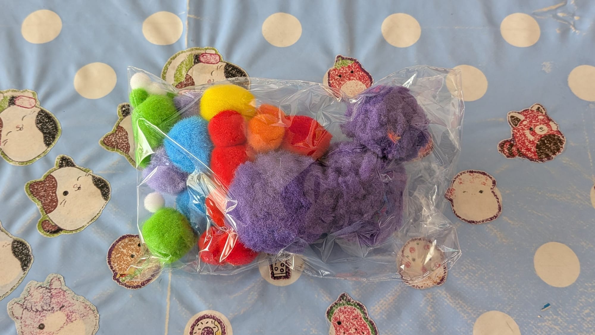 A selection of coloured cotton balls in a bag, on a table.